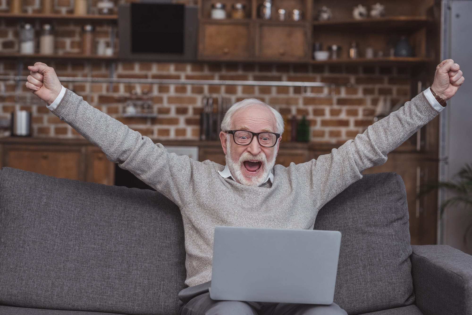 Happy grey hair man watching on laptop at home and celebrate win a bet with a gambling, soccer bet,